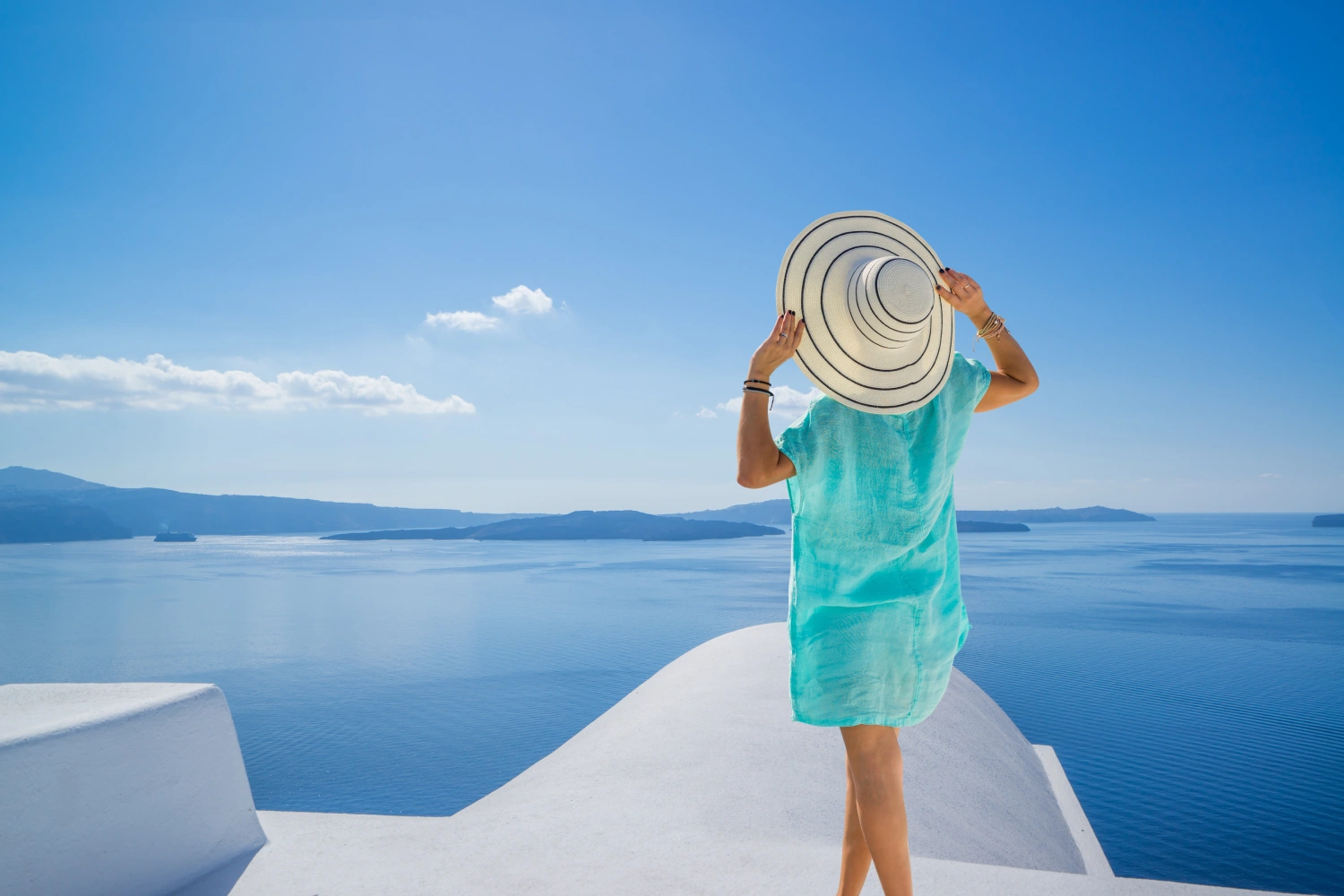 Frau auf einer Terrasse mit Blick auf die Caldera in Santorini, Griechenland
