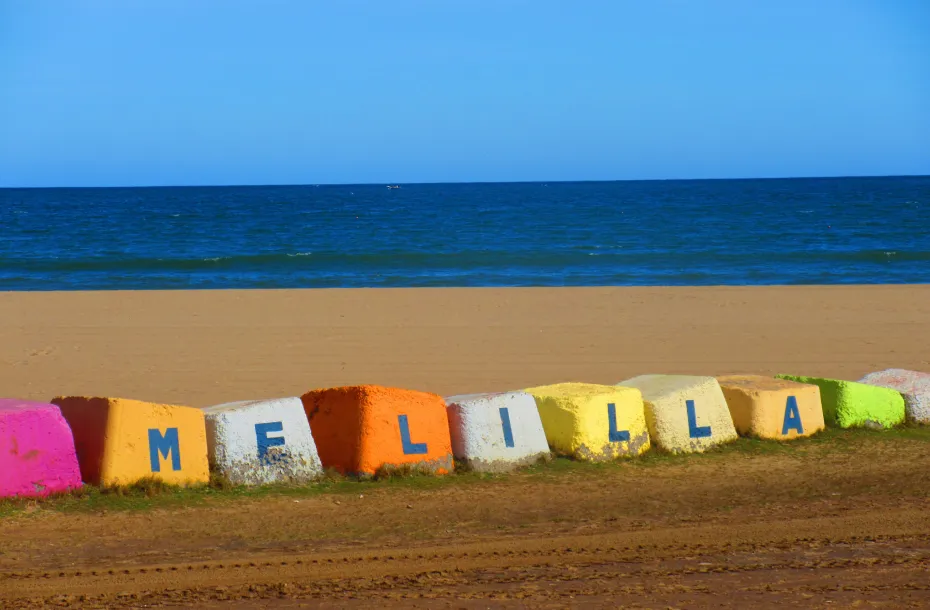 Mehrfarbige Steine ​​am Strand, die den Namen von Melilla bilden.