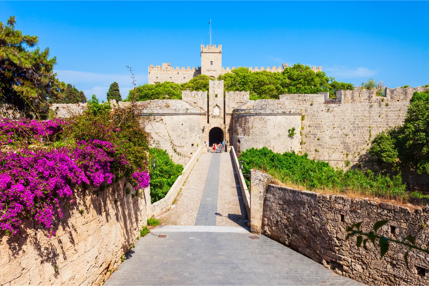 Der Weg zur dominierenden Burg von Rhodos mit Blumen und üppiger Vegetation ringsum