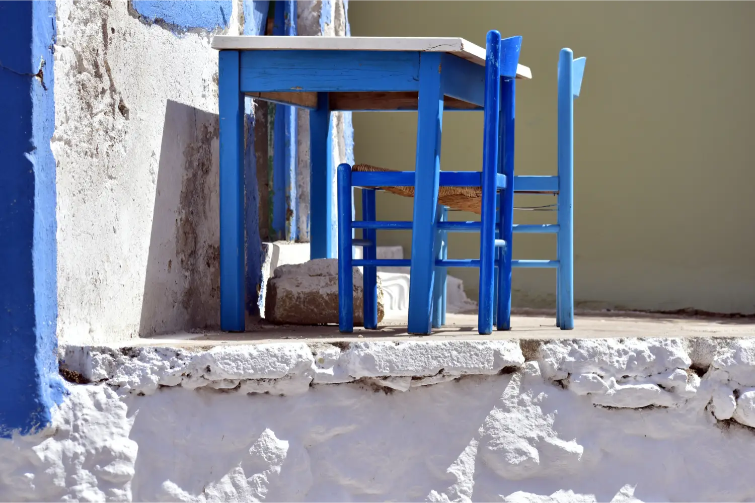 Ein blauer Tisch und ein Stuhl vor einem traditionellen Haus in Pigadia, Karpathos
