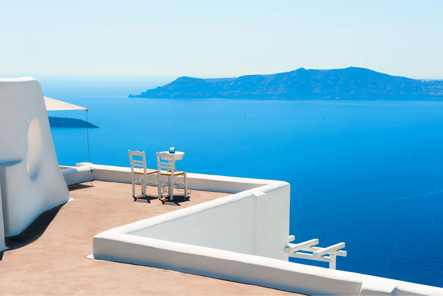 Zwei Stühle auf der Terrasse mit Blick auf die Caldera in Santorin