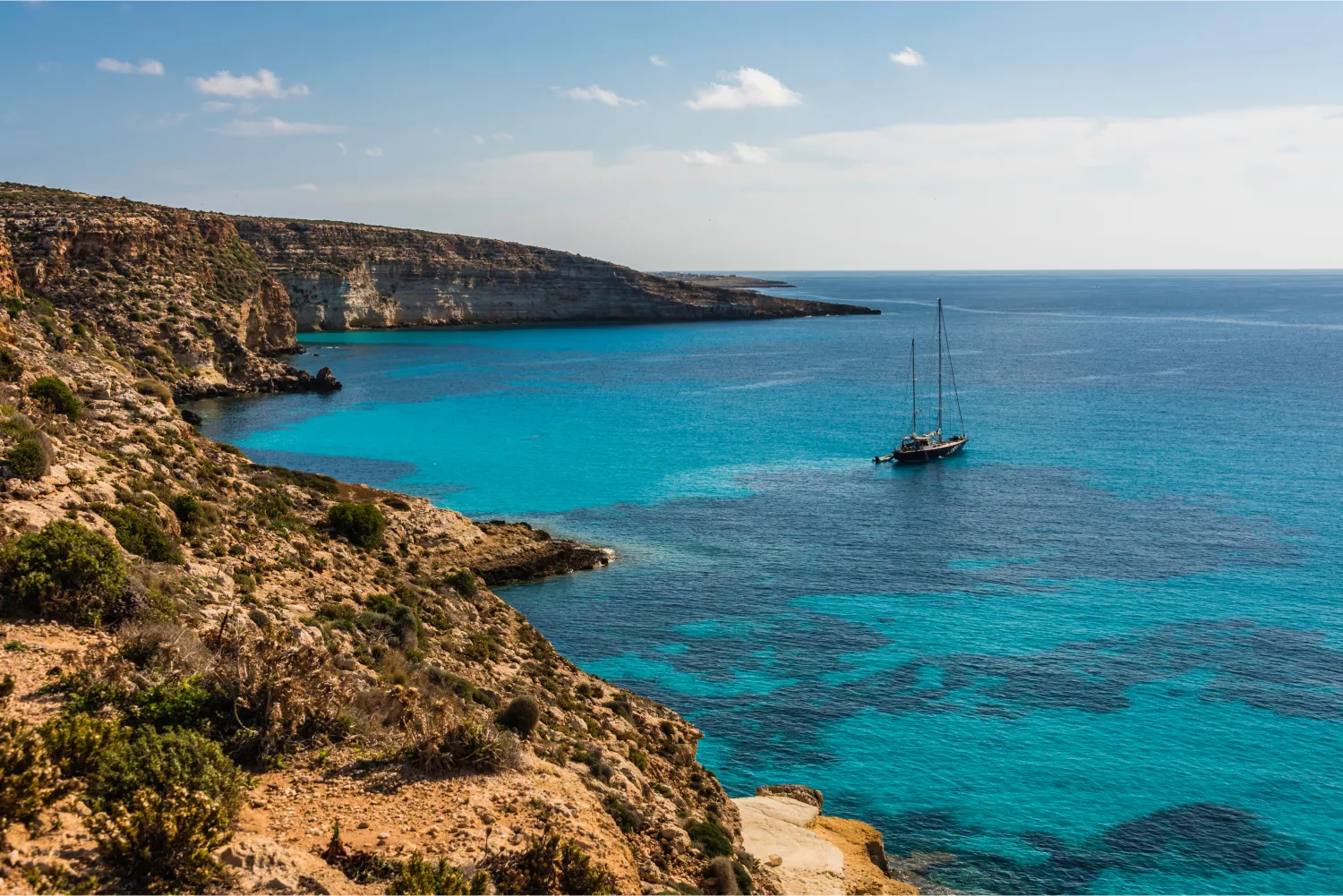 Der außergewöhnliche Kaninchenstrand in Lampedusa und ein Segelboot, das abfährt
