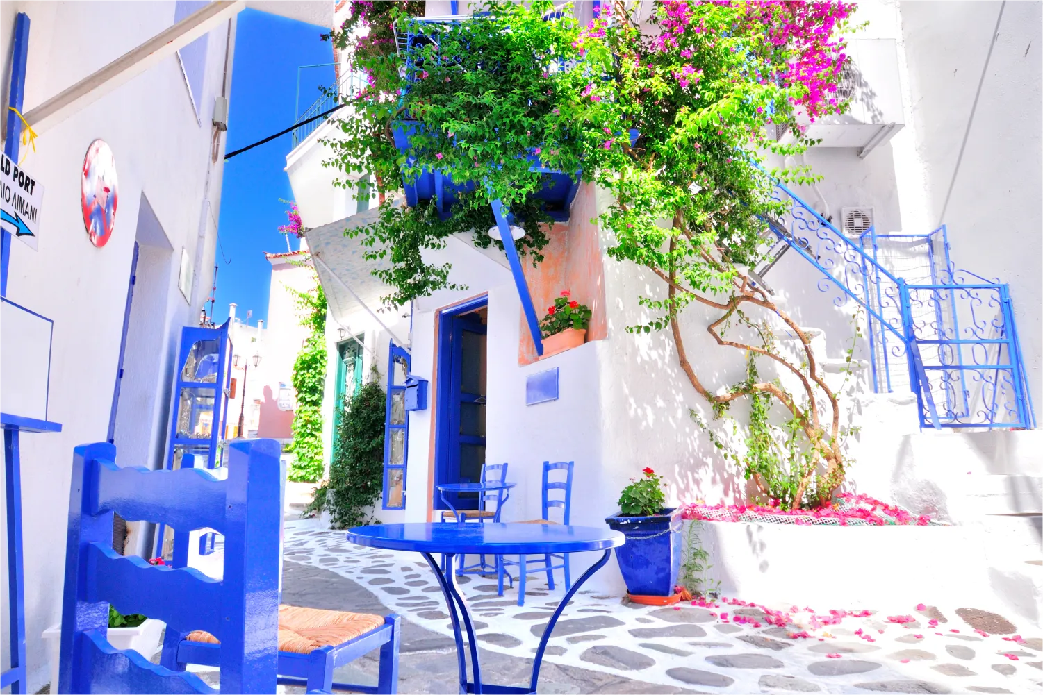 Weiße Wände, blaue Möbel und bunte Bougainvilla im Dorf Skiathos