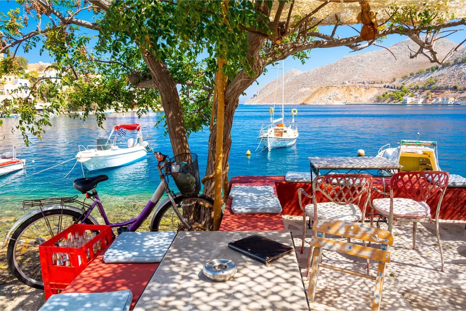 Ein geparktes Fahrrad in einem bunten Café neben dem Fischereihafen von Symi