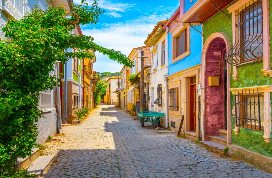 Charmante gepflasterte Straße mit bunten Häusern und Pflanzen in Ayvalik, Türkei