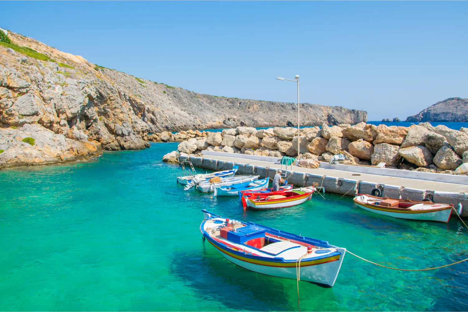 Kleiner Hafen mit bunten Fischerbooten und türkisfarbenem Wasser im Dorf Potamos in Antikythira