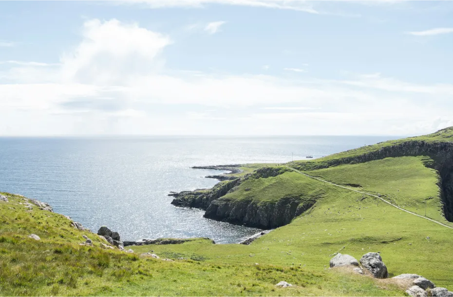 Fantastische Aussicht auf grüne Felder über dem Meer in Schottland