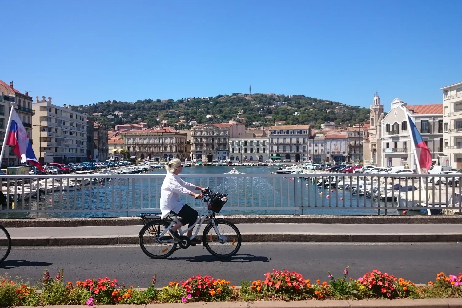 Frau fährt mit dem Fahrrad entlang des Hafens von Sete