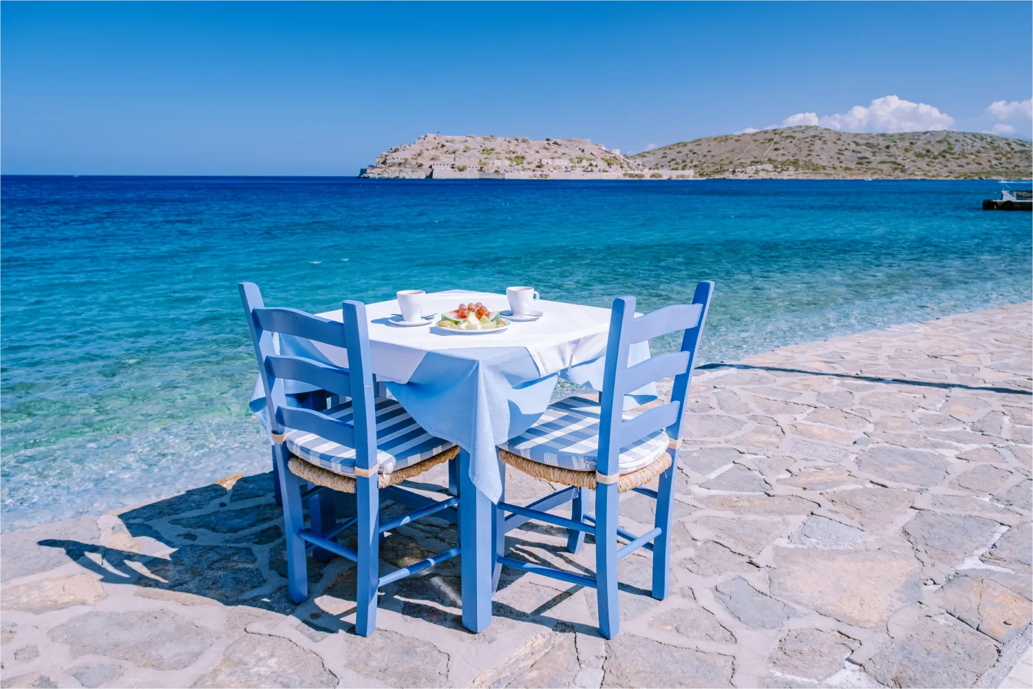 Traditioneller blauer Tisch und Stühle und der Strand in Lasithi