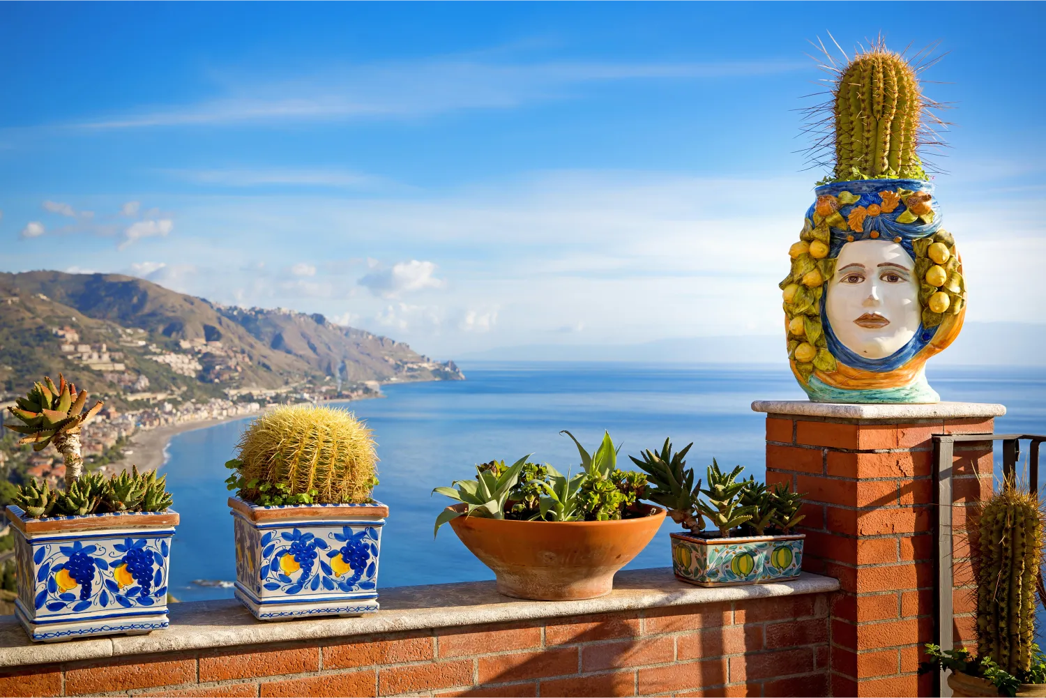 Blumentöpfe auf einem Balkon in Sizilien und schöne Aussicht auf die Küste Taormina im Hintergrund