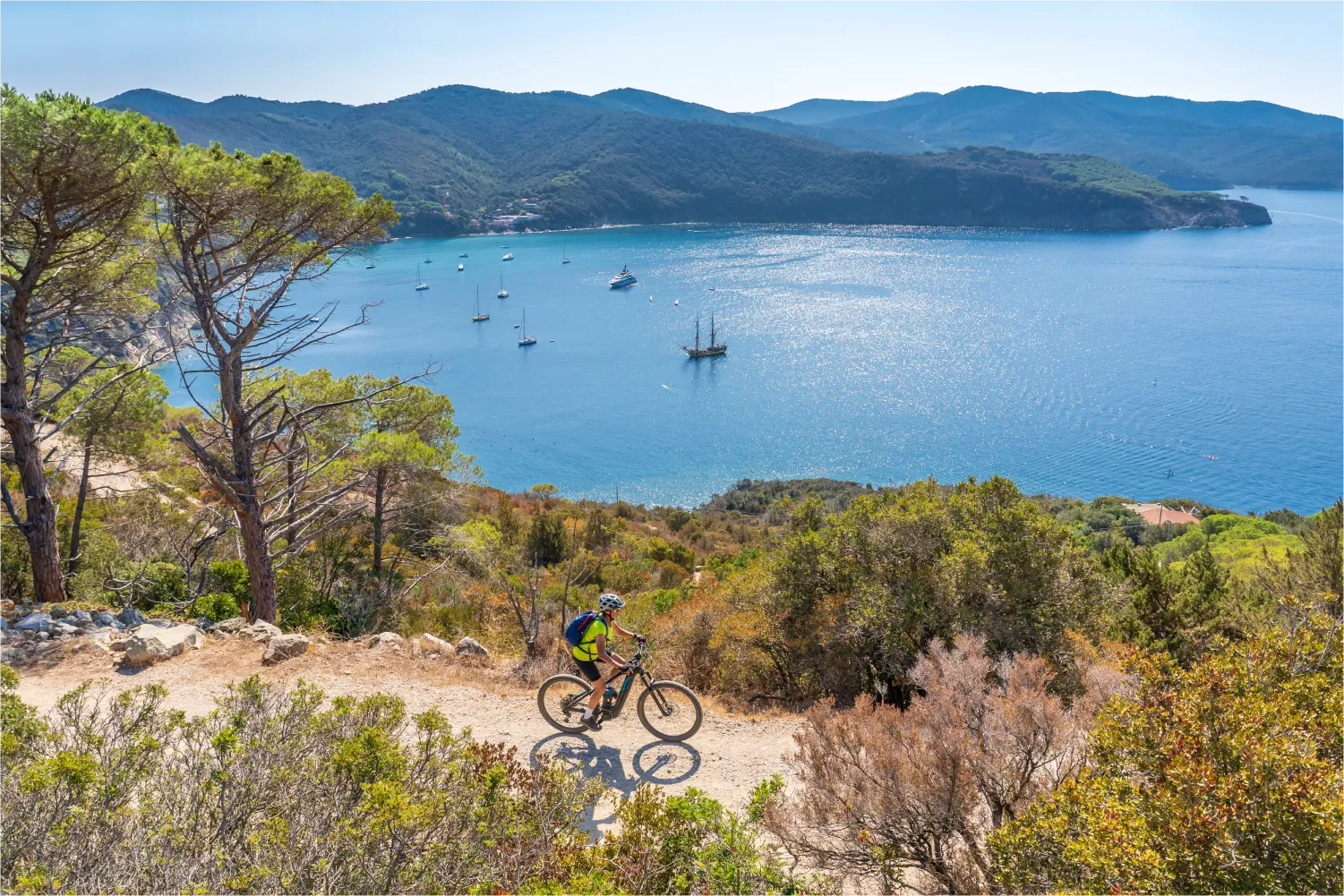 Frau fährt mit ihrem elektrischen Mountainbike an der Küste von Elba vor Portoferraio